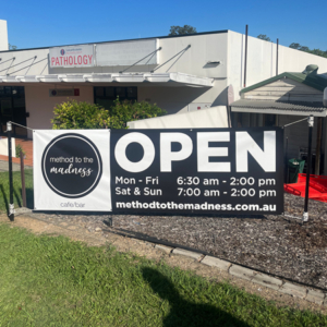 Method to the Madness - Vinyl Banner A vinyl banner for Method to the Madness on display in front of their building, facing the road. It features big "OPEN" text, as well as their opening hours and website.