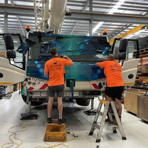 Signosaur Installations - Tadano Hybrid Crane Wrap Two Signosaur Installations team members working on the cab section of a crane wrap.