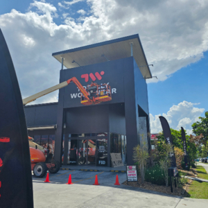Totally Workwear North Lakes - Shop Front - Installation Service A Signosaur Installations team member in a scissor lift installing ACP for Totally Workwear North Lakes - Shop Front