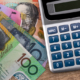 Australian $100 note, $10 note, $5 note, and $10 note on a table with a calculator