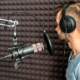 A man in a sound recording booth doing a voiceover