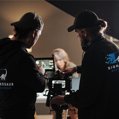 Two Signosaur Media Group staff members video recording the talent